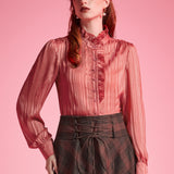 Woman wearing dusty rose ruffle button-front blouse tucked into a brown plaid corset-waist skirt against a pink background