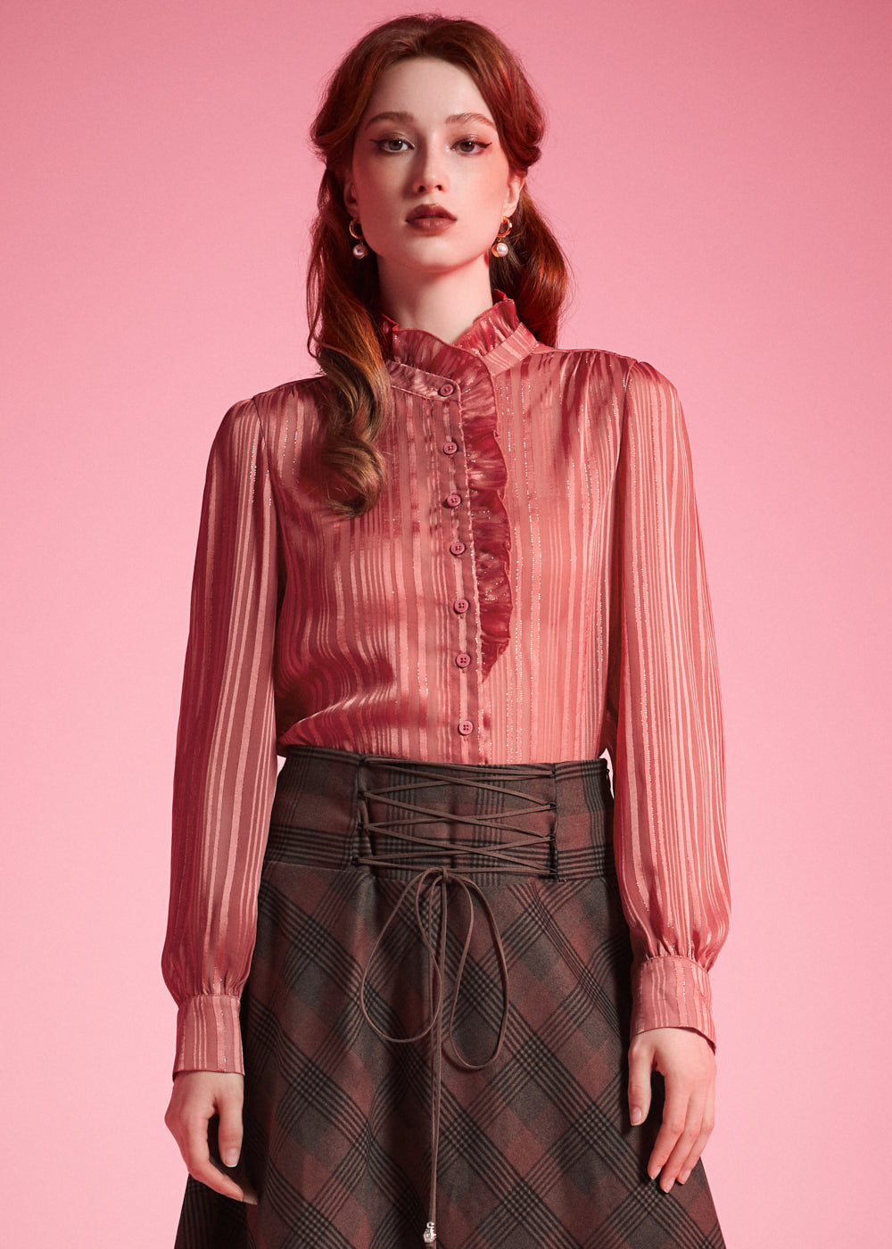 Front view of woman wearing dusty rose striped blouse with high ruffle neck, button placket, and long blouson sleeves
