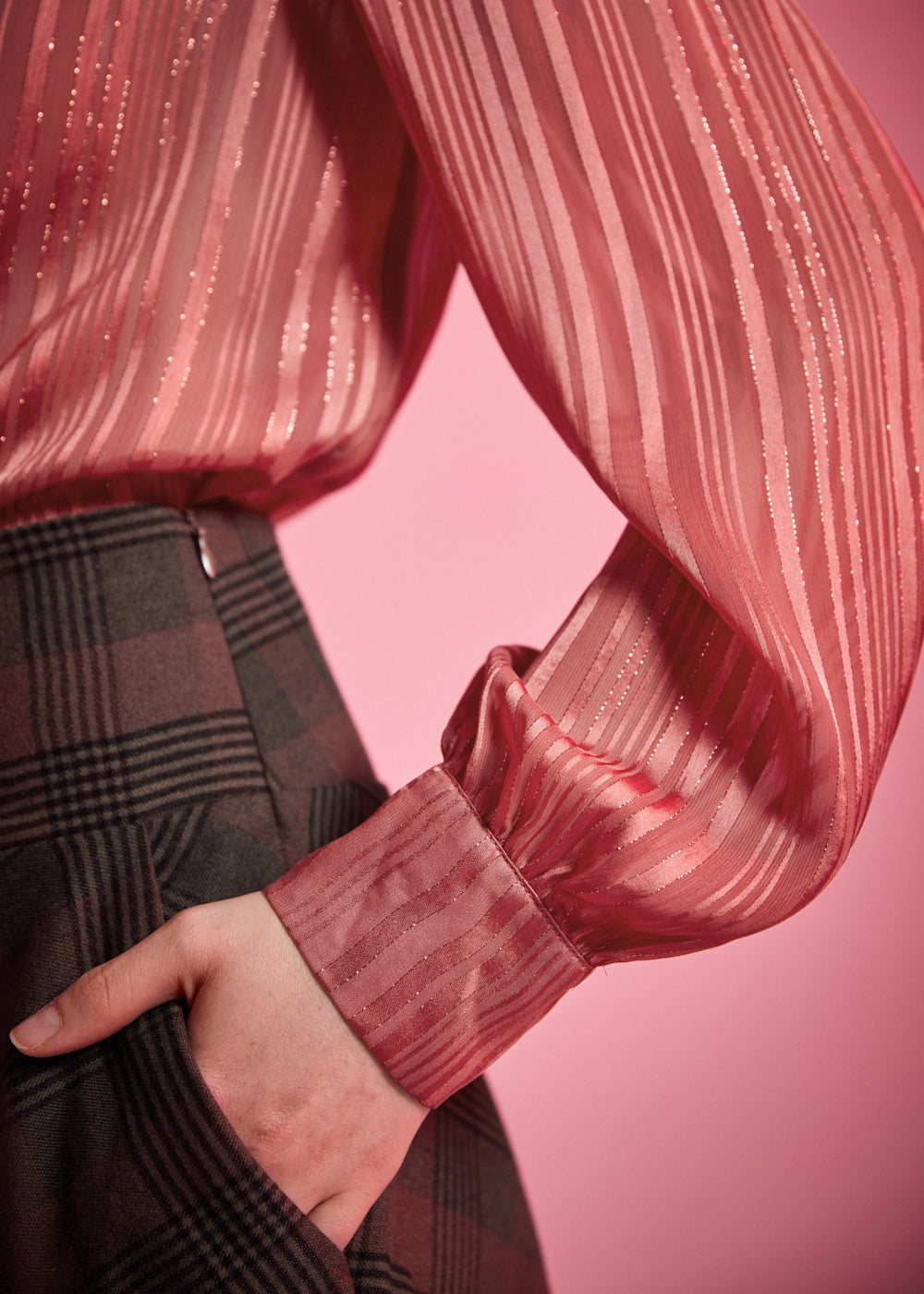 Close-up of woman wearing dusty rose striped blouse showing the long gathered sleeve, shimmering fabric, and wide button cuff