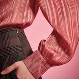 Close-up of woman wearing dusty rose striped blouse showing the long gathered sleeve, shimmering fabric, and wide button cuff