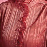 Close-up of dusty rose ruffle blouse showing the high ruffled neckline, button front, gathered shoulder, and shimmering tonal stripes