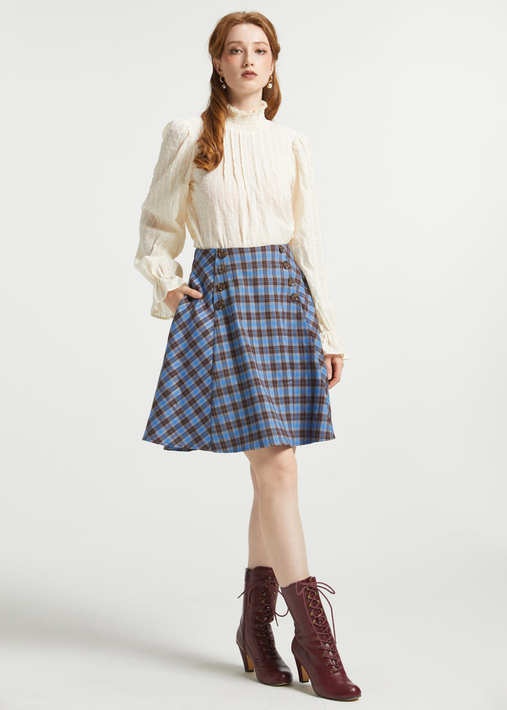 Woman wearing Poetry in Motion Blouse with high ruffle neck, long gathered sleeves and blue plaid skirt