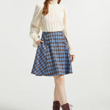 Woman wearing Poetry in Motion Blouse with high ruffle neck, long gathered sleeves and blue plaid skirt