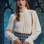 Woman wearing ivory Victorian-inspired long sleeve blouse tucked into a blue plaid A-line skirt