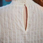 Close-up of back of cream color poet blouse showing three-button neck closure, smocked collar and keyhole opening