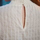 Close-up of back of cream color poet blouse showing three-button neck closure, smocked collar and keyhole opening