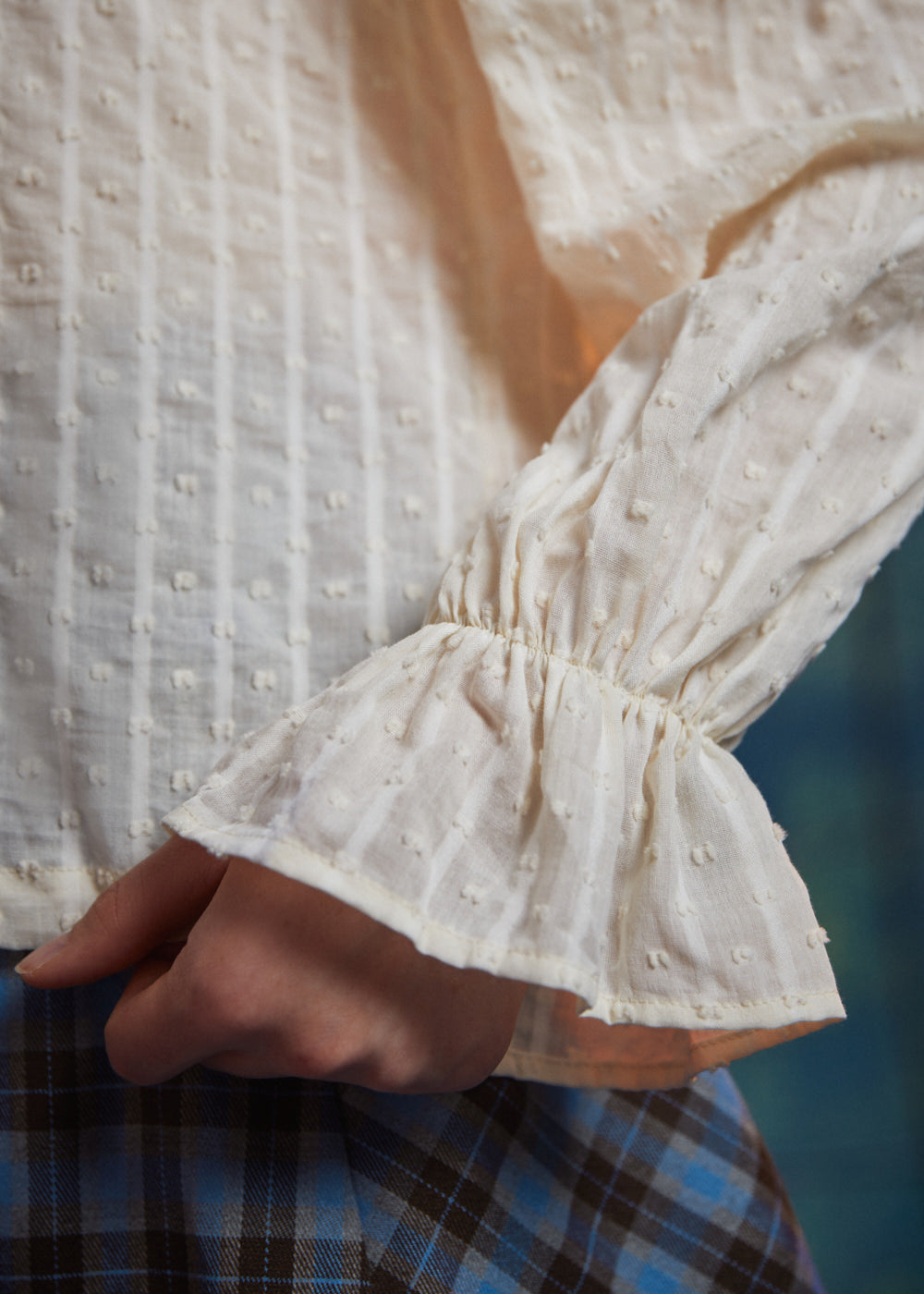 Close-up of cream dobby striped poet blouse sleeve showing elasticized wrist and flared ruffle cuff