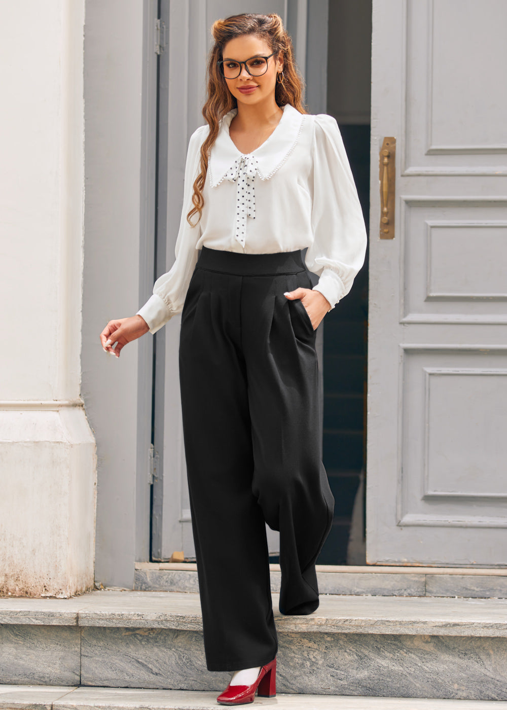 Full-length view of woman wearing ivory tie neck blouse with black wide-leg trousers and red heels