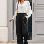 Full-length view of woman wearing ivory tie neck blouse with black wide-leg trousers and red heels