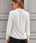 Back view of ivory long sleeve blouse showing oversized collar with pom-pom trim and gathered shoulders