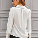 Back view of ivory long sleeve blouse showing oversized collar with pom-pom trim and gathered shoulders