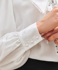 Close-up of ivory long sleeve blouse with gathered sleeve and three-button cuff