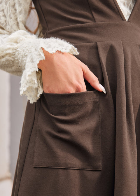 Woman showing the oversized front patch pocket on the brown Layer It On Me Jumper with pleated skirt.