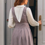 Back view of woman wearing houndstooth jumper dress with deep V-back