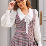 Woman wearing burgundy houndstooth jumper dress with deep V-neck and gold-tone buttons