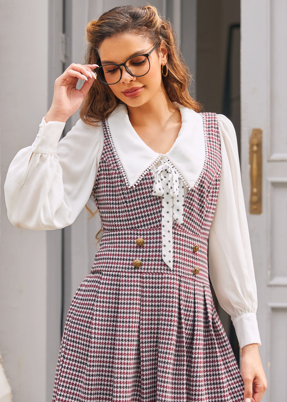 Woman wearing burgundy houndstooth jumper dress with deep V-neck and gold-tone buttons