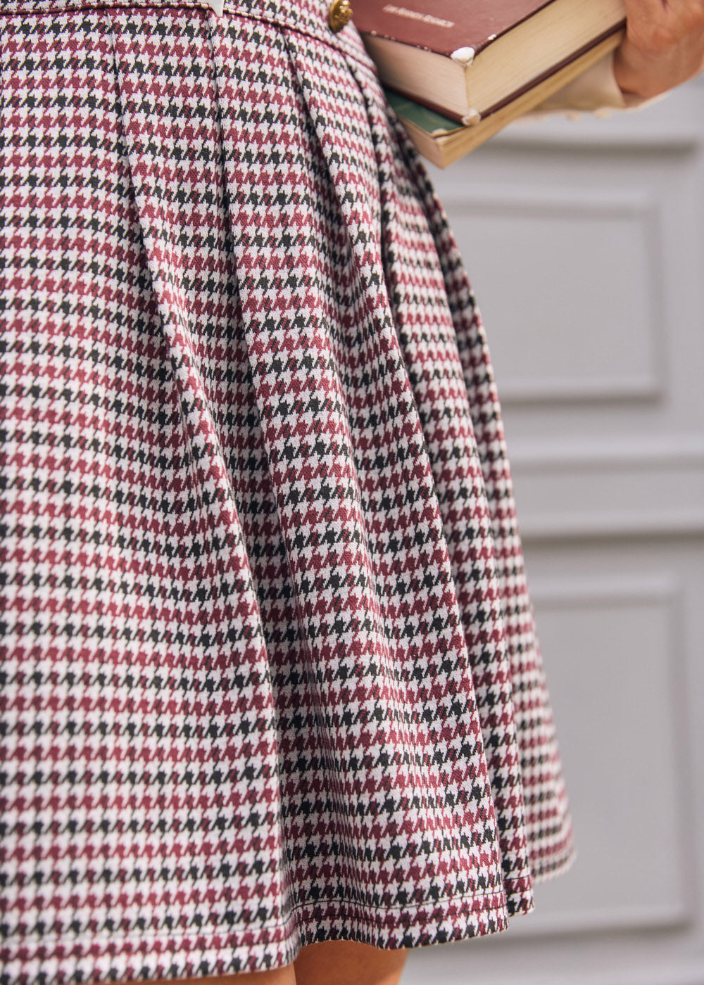 Close-up of pleated skirt on burgundy black and cream houndstooth jumper dress