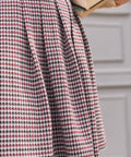 Close-up of pleated skirt on burgundy black and cream houndstooth jumper dress