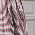 Close-up of pleated skirt on burgundy black and cream houndstooth jumper dress