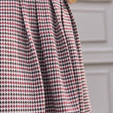 Close-up of pleated skirt on burgundy black and cream houndstooth jumper dress