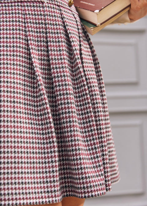 Close-up of pleated skirt on burgundy black and cream houndstooth jumper dress