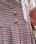 Close-up of burgundy houndstooth jumper dress with decorative gold-tone buttons
