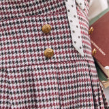 Close-up of burgundy houndstooth jumper dress with decorative gold-tone buttons