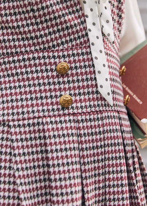 Close-up of burgundy houndstooth jumper dress with decorative gold-tone buttons