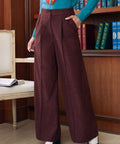 Three-quarter view of woman wearing Mahogany Wine high waisted corduroy wide leg pants with teal sweater in library