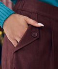 Close-up of woman wearing Mahogany Wine corduroy pants showing functional side pocket with button-tab detail