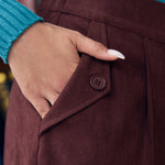 Close-up of woman wearing Mahogany Wine corduroy pants showing functional side pocket with button-tab detail