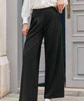 Woman wearing black high waisted wide leg trousers with front pleats and red block heel shoes