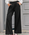 Woman wearing black wide leg trousers with high waist and hands in functional side pockets