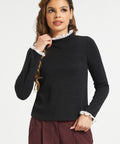 Woman wearing black lace trim mock neck top with long sleeves and burgundy trousers against white studio background