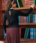 Back view of woman wearing black mock neck top showing keyhole opening and white lace collar trim