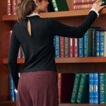 Back view of woman wearing black mock neck top showing keyhole opening and white lace collar trim