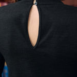 Close-up of black mock neck top with back keyhole and two button closures trimmed with white lace