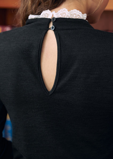 Close-up of black mock neck top with back keyhole and two button closures trimmed with white lace