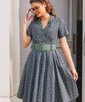Woman wearing Forget Me Not floral cotton dress showing piped notched collar, button front and wide sage green belt