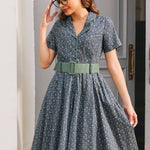 Woman wearing Forget Me Not floral cotton dress showing piped notched collar, button front and wide sage green belt