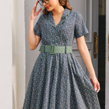 Woman wearing Forget Me Not floral cotton dress showing piped notched collar, button front and wide sage green belt
