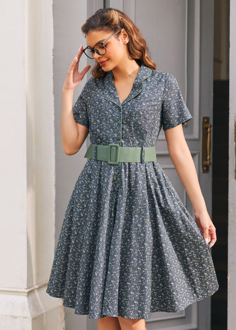 Woman wearing Forget Me Not floral cotton dress showing piped notched collar, button front and wide sage green belt