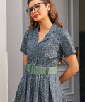 Close-up of woman wearing Rustic Elegance cotton floral dress in Forget Me Not with side pocket and sage green belt