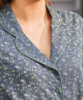 Close-up of woman wearing vintage-inspired blue floral dress showing notched collar, sage green piping and button front
