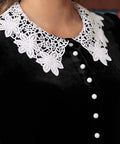 Close-up of black velvet dress with white floral lace collar and contrast buttons