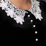 Close-up of black velvet dress with white floral lace collar and contrast buttons