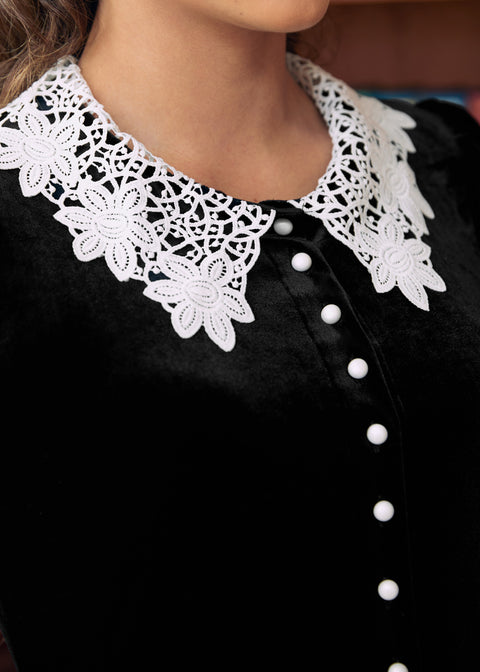 Close-up of black velvet dress with white floral lace collar and contrast buttons
