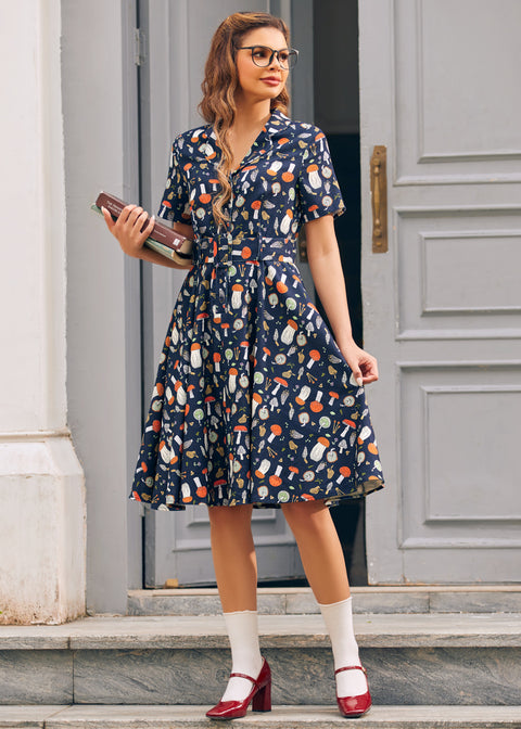 Woman wearing vintage inspired mushroom print dress with notched collar, short sleeves and pleated skirt