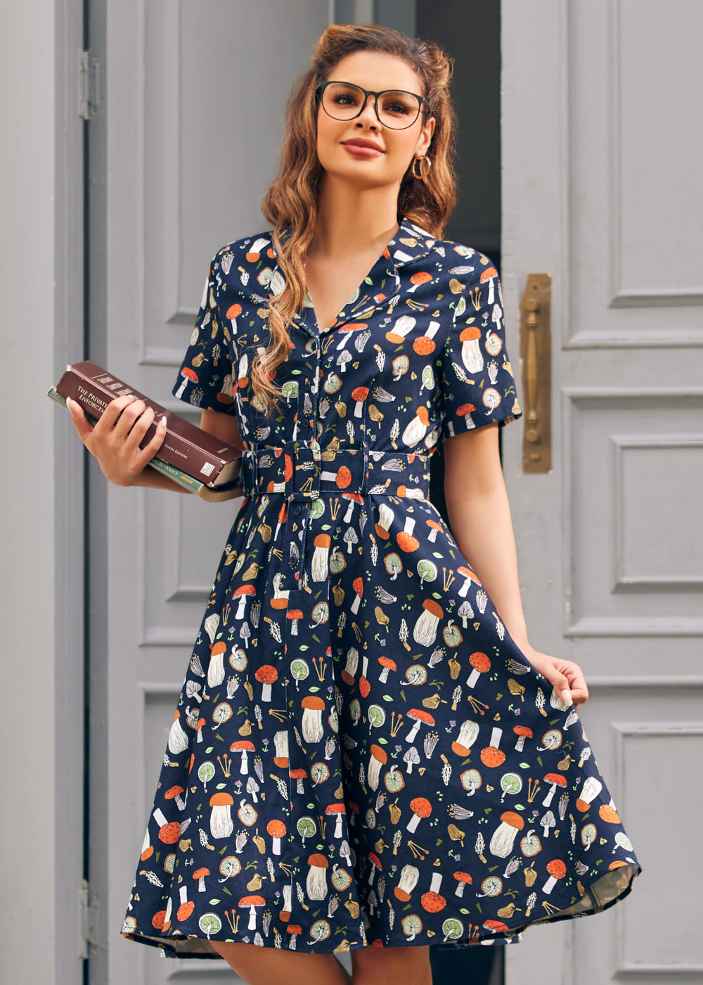 Woman wearing ModCloth navy mushroom print fit and flare dress with button front, belt and pockets