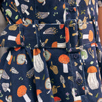 Close-up of a navy blue fabric shirtdress with an allover mushroom print in orange, white, beige, and green, featuring a matching fabric belt with a covered buckle.